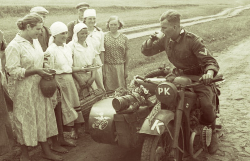 Украинские жители встречают немецкого фотографа из Роты Пропаганды. Обращает внимание утка на люльке мотоцикла, как значок Рот Пропаганды. Аббревиатура PK — Propaganda Kompanie переводится как Рота Пропаганды. Источник: Bundesarchiv, Bild 101I-187-0203-23 / Gehrmann, Friedrich / CC-BY-SA 3.0